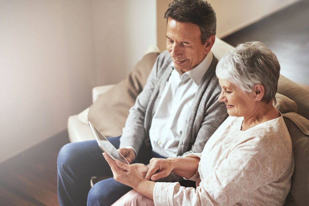 Senior man and woman seated on couch looking at an iPad